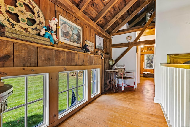 hallway featuring lofted ceiling with beams, light wood-style floors, wood ceiling, and a wealth of natural light