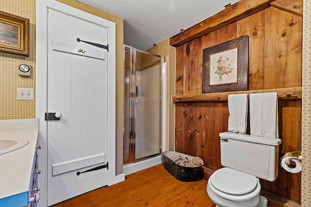 bathroom featuring toilet, a stall shower, wood finished floors, and vanity