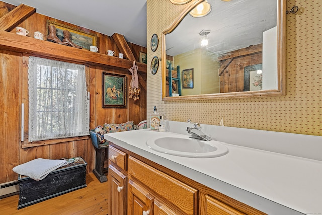 bathroom with wood walls, baseboard heating, wood finished floors, and vanity