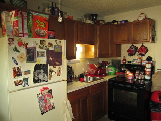 kitchen with sink, black electric range oven, white fridge, and a textured ceiling