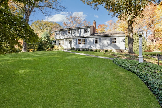 view of front of home with a chimney and a front lawn