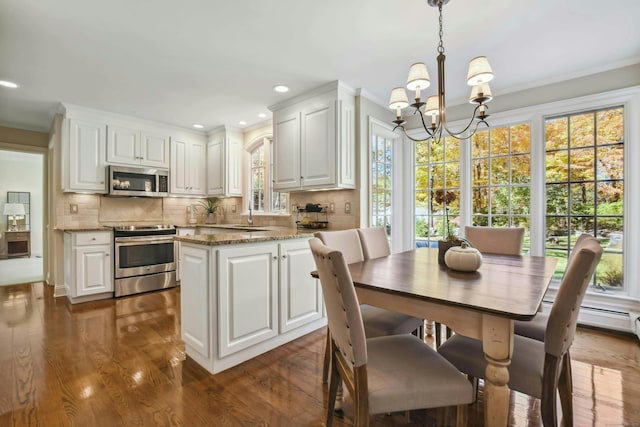 kitchen featuring appliances with stainless steel finishes, white cabinetry, and hanging light fixtures