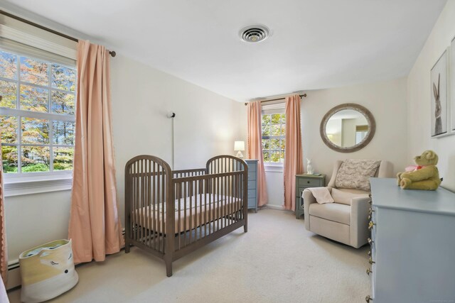 bedroom featuring light colored carpet, visible vents, and a nursery area