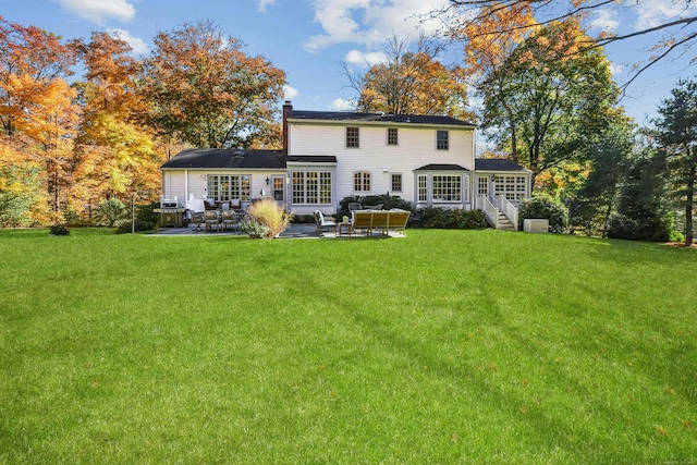 back of house featuring a yard, a chimney, a patio area, and an outdoor living space