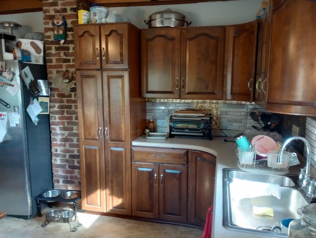 kitchen with sink, decorative backsplash, and stainless steel refrigerator