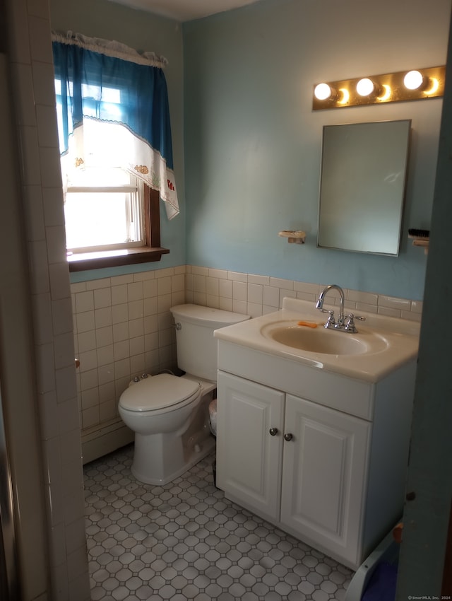 bathroom featuring vanity, toilet, tile walls, and tile patterned flooring