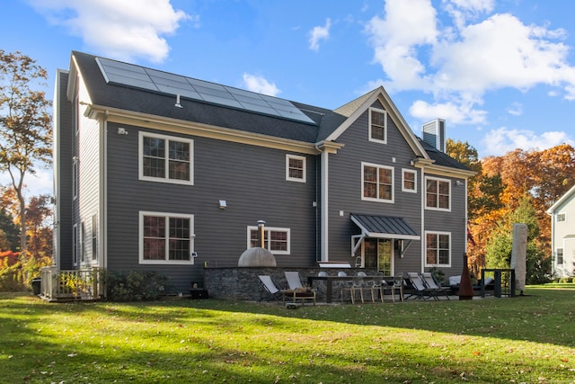 back of house featuring a patio, solar panels, and a lawn