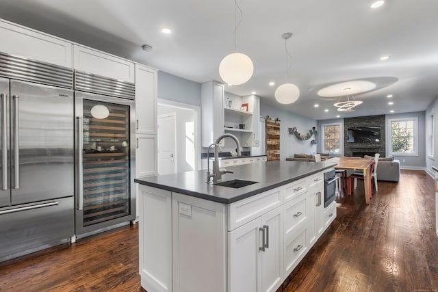 kitchen with a stone fireplace, dark hardwood / wood-style floors, sink, white cabinetry, and appliances with stainless steel finishes