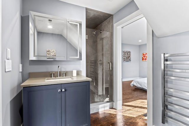 bathroom with vanity, radiator, wood-type flooring, and a shower with door