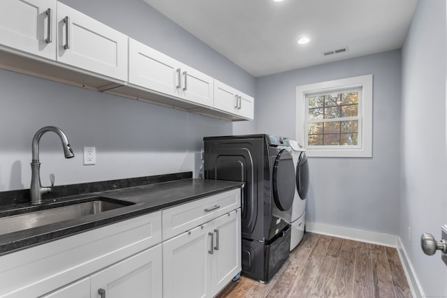 washroom featuring light hardwood / wood-style floors, cabinets, sink, and separate washer and dryer