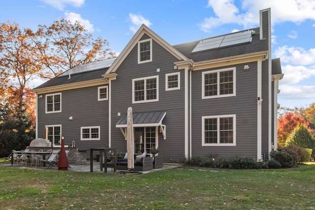 back of house with a patio area, outdoor lounge area, solar panels, and a lawn