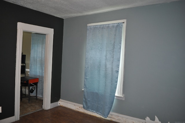 unfurnished bedroom with a closet, a textured ceiling, and dark hardwood / wood-style flooring