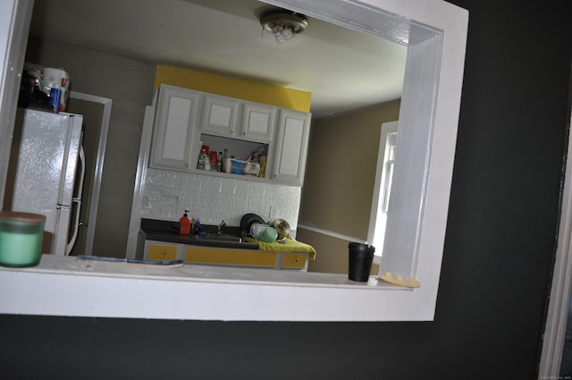 kitchen with white fridge, backsplash, sink, and white cabinets