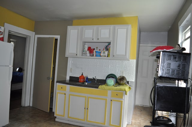 kitchen with sink, white cabinetry, white fridge, and backsplash