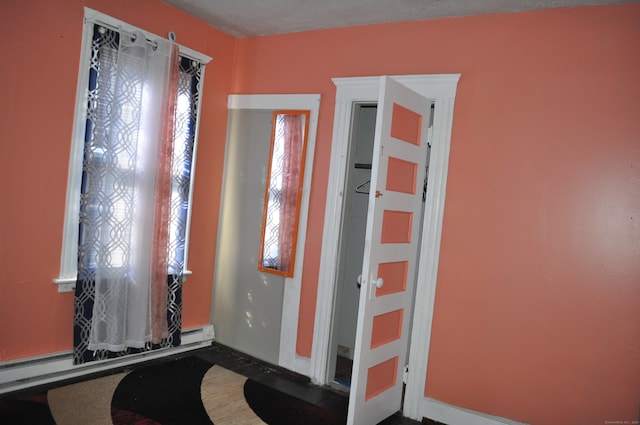 foyer featuring a healthy amount of sunlight, a textured ceiling, and baseboard heating