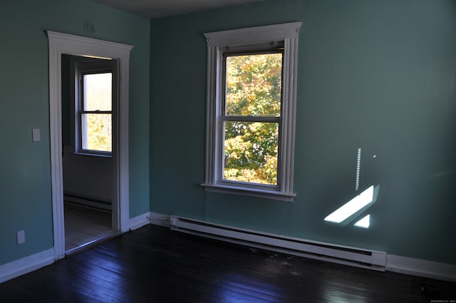 unfurnished room featuring a baseboard heating unit and dark hardwood / wood-style floors