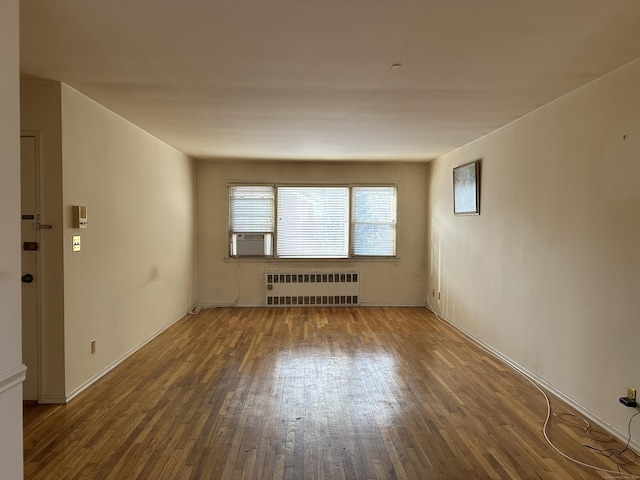 spare room featuring dark wood-type flooring and radiator heating unit