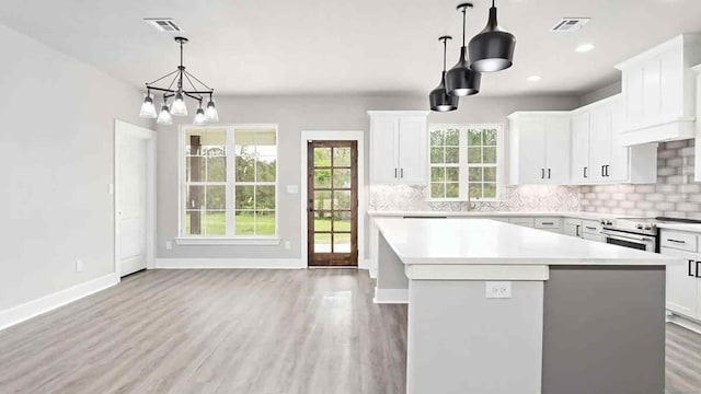 kitchen featuring light hardwood / wood-style flooring, white cabinets, a center island, hanging light fixtures, and stainless steel electric range