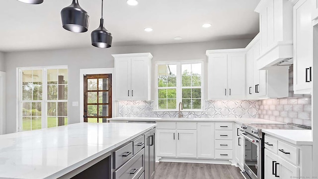 kitchen featuring electric range, decorative backsplash, white cabinetry, and hanging light fixtures