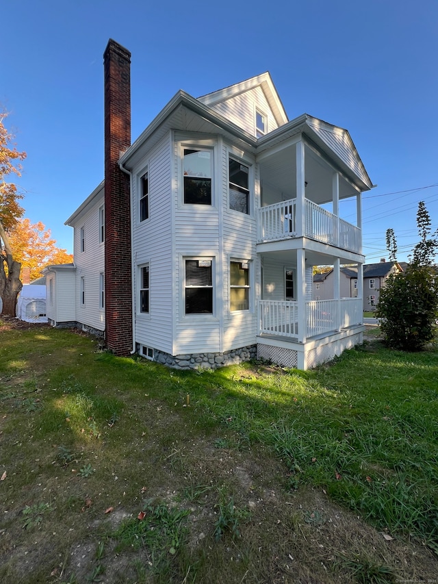 back of house with a lawn and a balcony