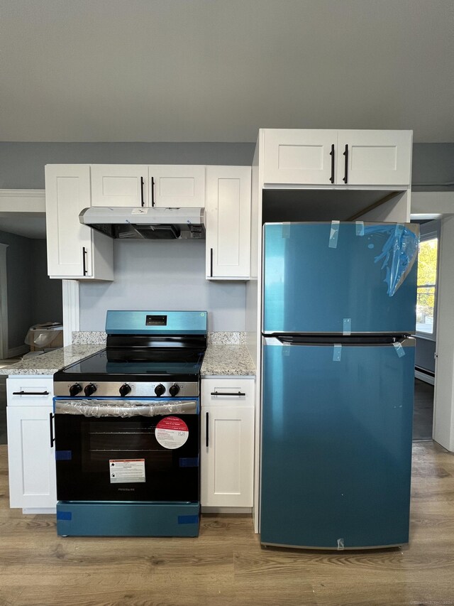 509 S Main St, Torrington, CT 06790 - kitchen featuring stainless steel electric stove, freestanding refrigerator, under cabinet range hood, and light wood-type flooring