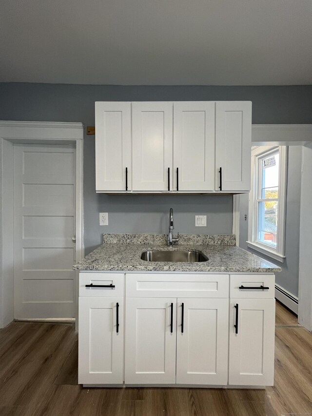 509 S Main St, Torrington, CT 06790 - kitchen with light stone countertops, a sink, white cabinets, and dark wood-type flooring