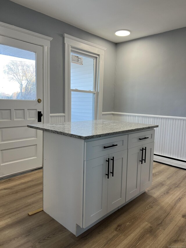 509 S Main St, Torrington, CT 06790 - kitchen featuring light stone countertops, wainscoting, and wood finished floors