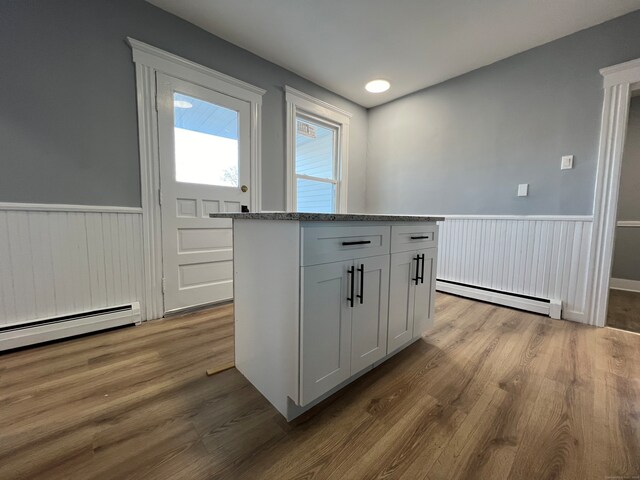 kitchen featuring a baseboard radiator, hardwood / wood-style floors, and white cabinets