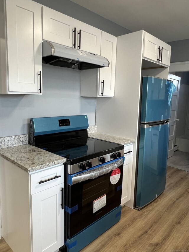 509 S Main St, Torrington, CT 06790 - kitchen featuring light wood-style flooring, freestanding refrigerator, under cabinet range hood, electric stove, and light stone countertops