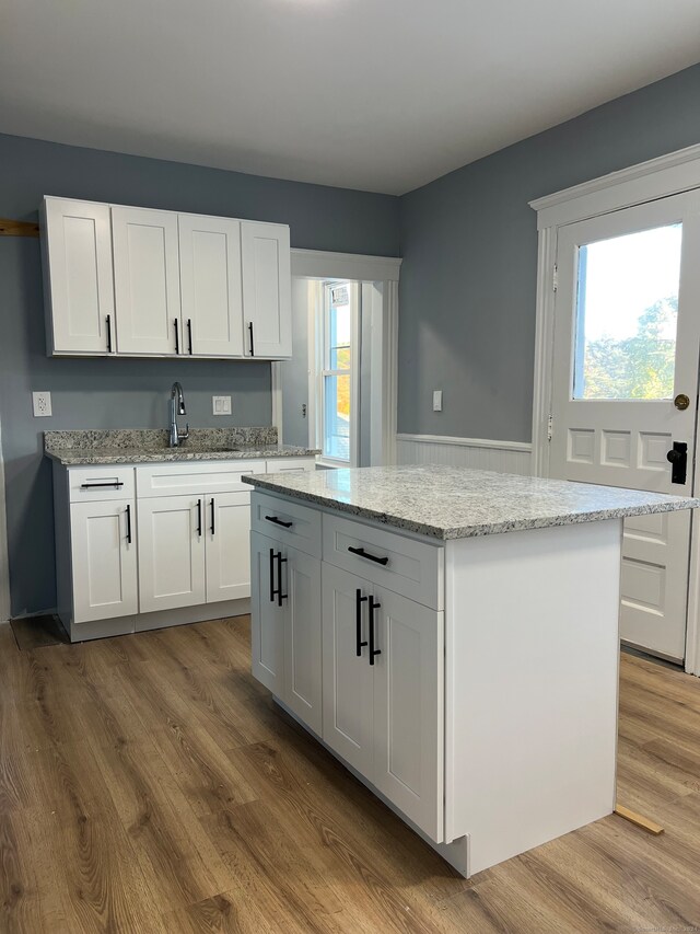 kitchen with white cabinetry, hardwood / wood-style flooring, and a healthy amount of sunlight