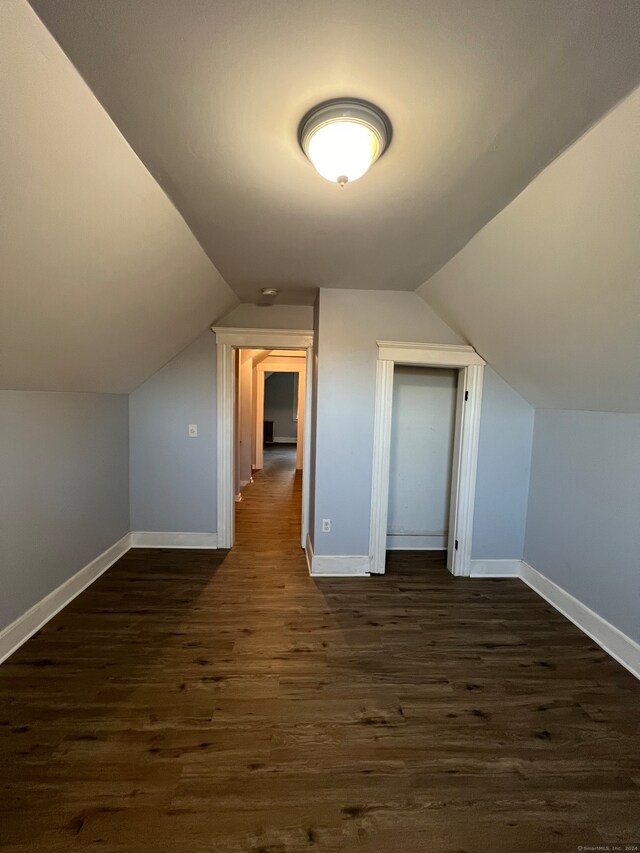 additional living space featuring dark wood-type flooring and vaulted ceiling