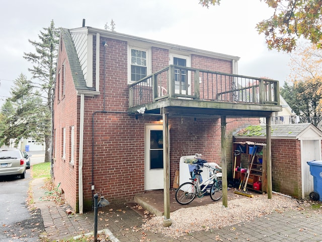 back of property featuring a storage shed and a balcony