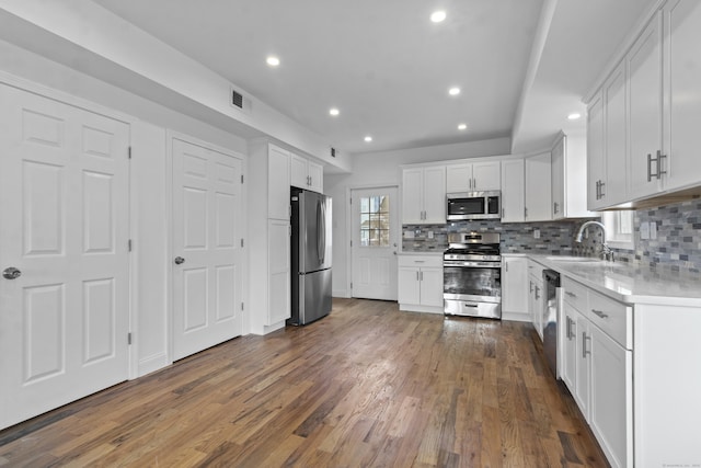 kitchen featuring white cabinetry, sink, dark wood-type flooring, stainless steel appliances, and tasteful backsplash