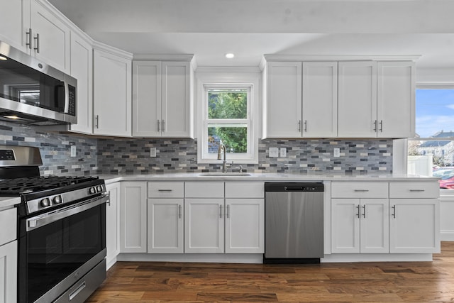 kitchen with white cabinets, decorative backsplash, sink, and stainless steel appliances