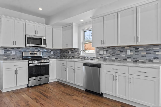 kitchen featuring backsplash, white cabinetry, sink, and appliances with stainless steel finishes