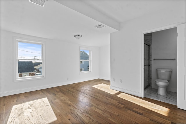 unfurnished bedroom with connected bathroom and dark hardwood / wood-style floors