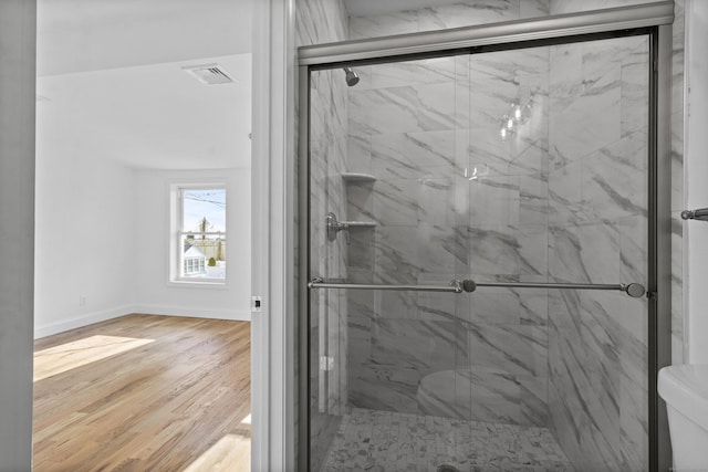 bathroom featuring hardwood / wood-style floors, toilet, and a shower with door