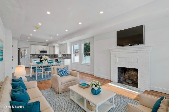 living room with light hardwood / wood-style floors and a brick fireplace