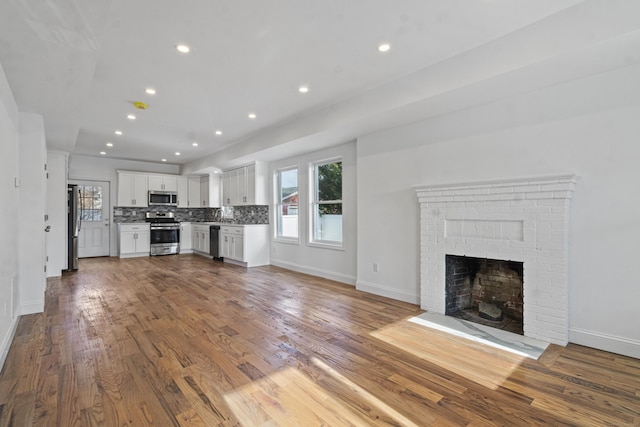 unfurnished living room featuring wood-type flooring and a brick fireplace