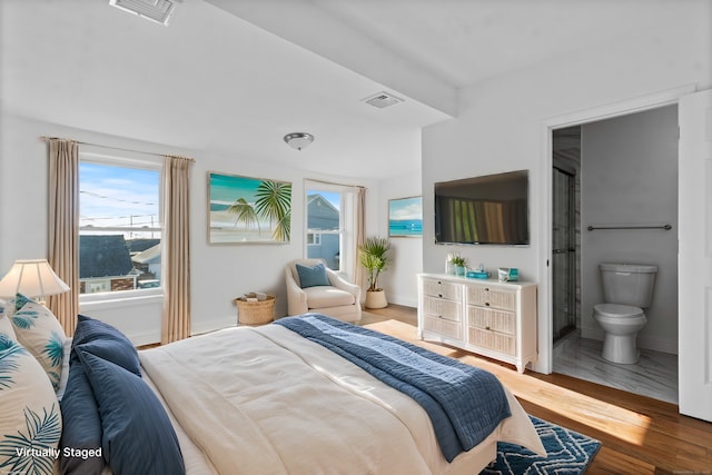 bedroom with hardwood / wood-style floors and ensuite bathroom