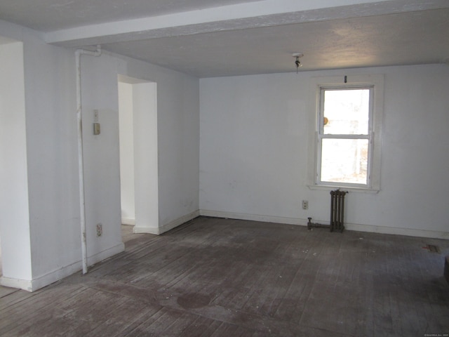 spare room with radiator heating unit and dark hardwood / wood-style floors