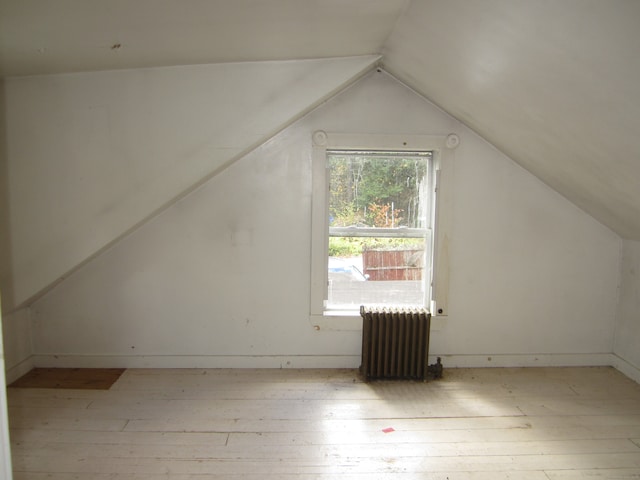 bonus room featuring lofted ceiling, radiator, and light wood-type flooring