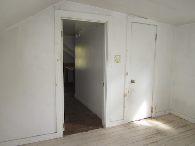 hallway with vaulted ceiling and light wood-type flooring