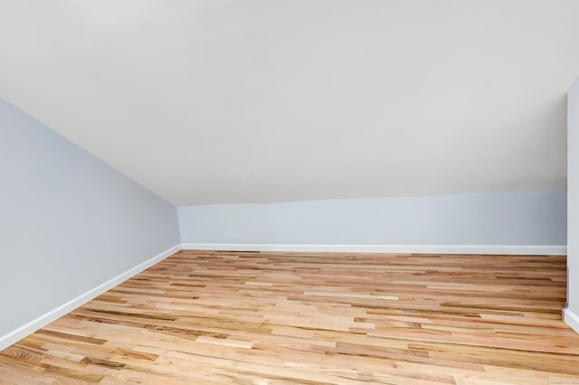 additional living space with light hardwood / wood-style floors and vaulted ceiling