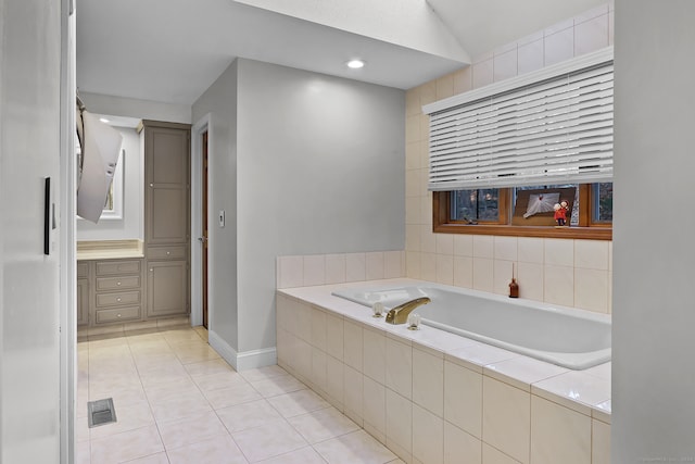 bathroom featuring vanity, a relaxing tiled tub, and tile patterned floors