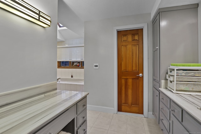 bathroom featuring vanity, tiled bath, tile patterned floors, and a skylight