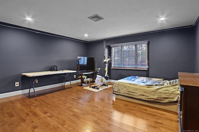 bedroom with ornamental molding and hardwood / wood-style flooring