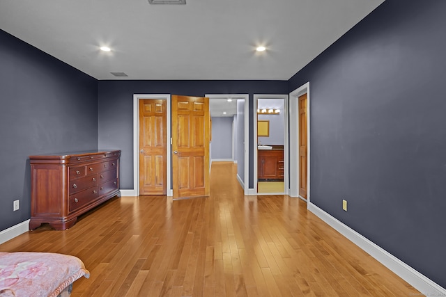 unfurnished bedroom with sink, ensuite bathroom, and light hardwood / wood-style flooring