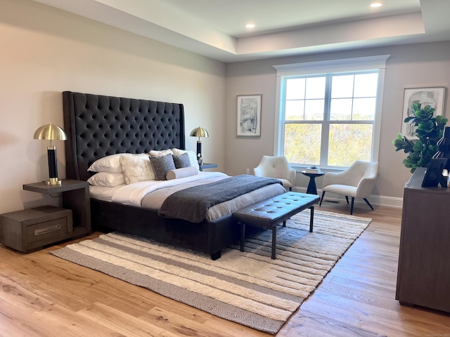 bedroom featuring light hardwood / wood-style floors and a raised ceiling