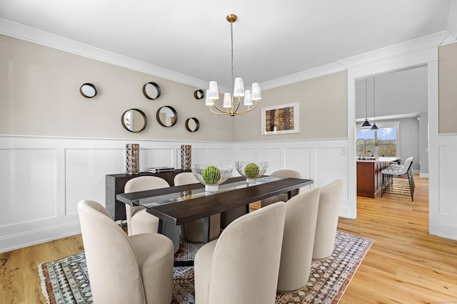 dining room with crown molding, hardwood / wood-style flooring, sink, and a notable chandelier